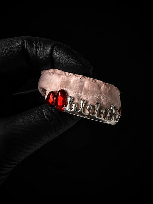 Angled view of custom sterling silver dripped grillz featuring red plated drip accents