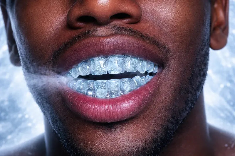 Close-up of a person with an iced grillz on his teeth