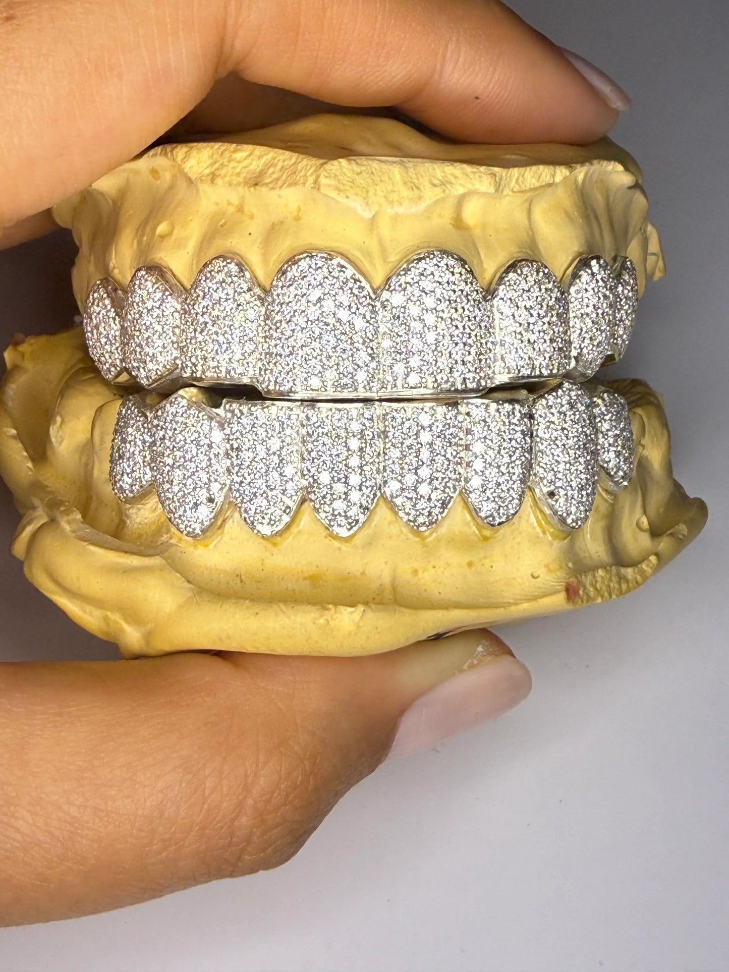Custom VVS-Moissanite bustdown grillz displayed on dental mold with luxury shine