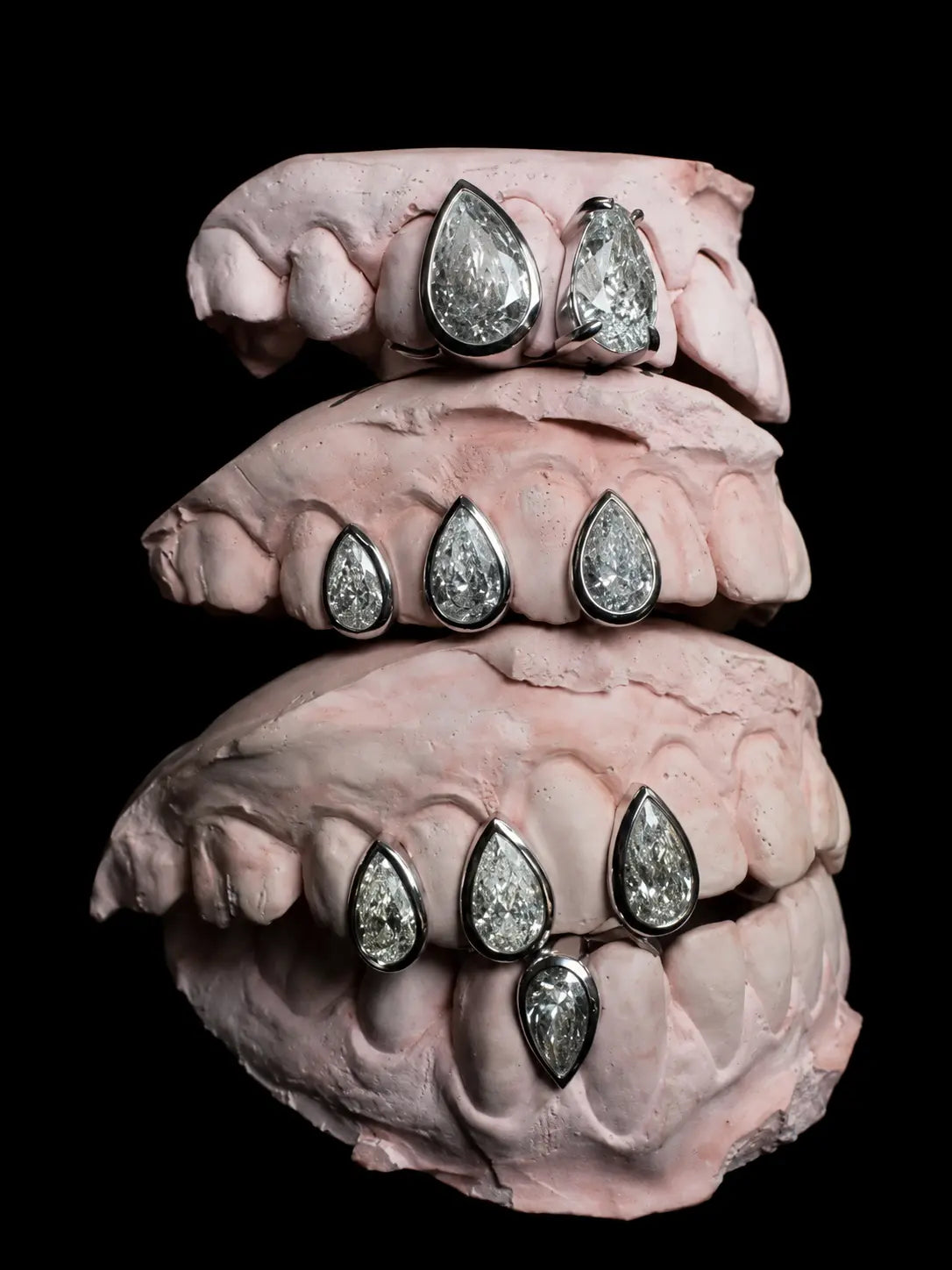 Custom pear-cut diamond grillz jewellery photographed on black background with luxury detailing