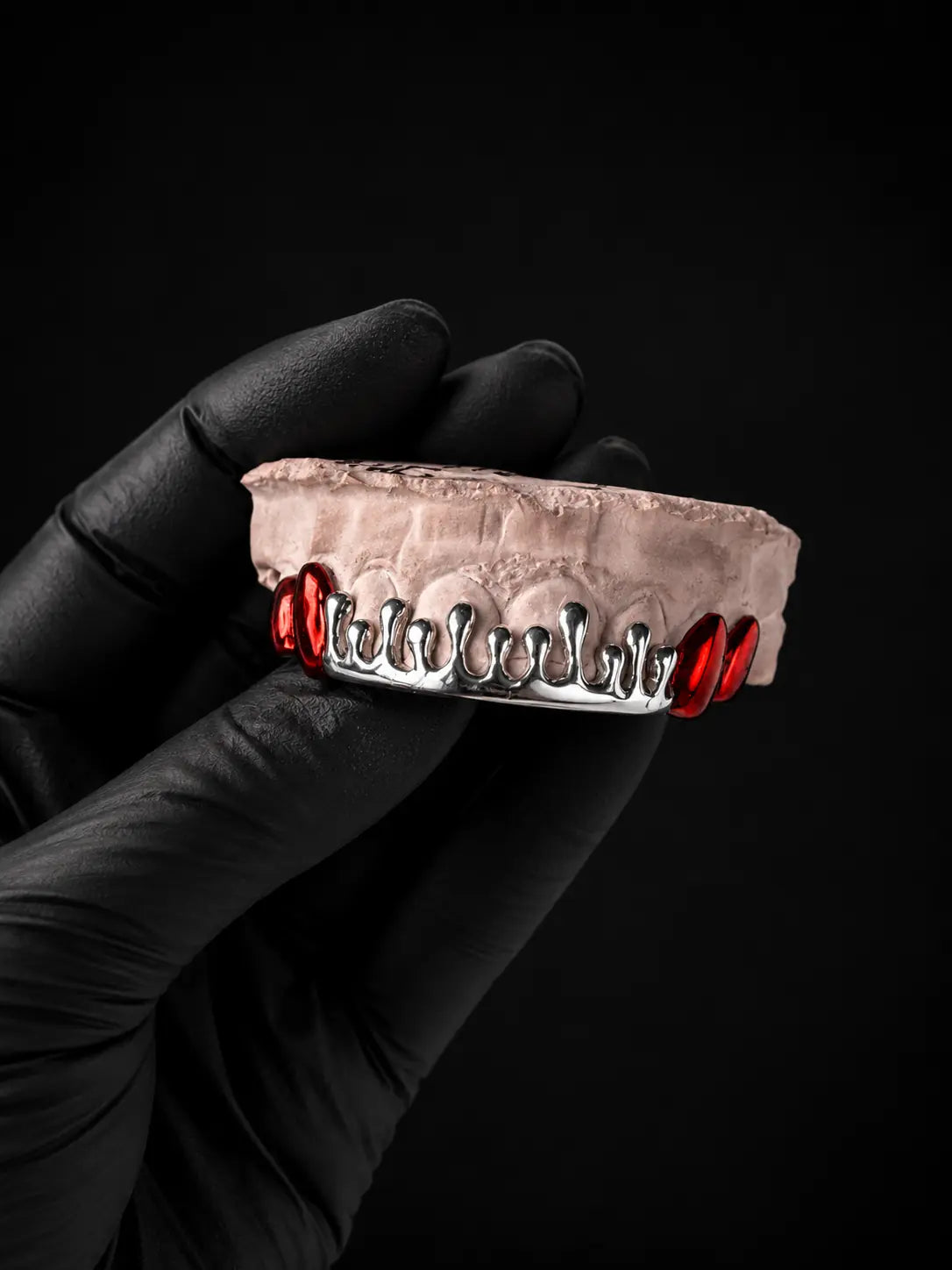 Custom handmade sterling silver dripped grillz with red plated drip accents on a dental model