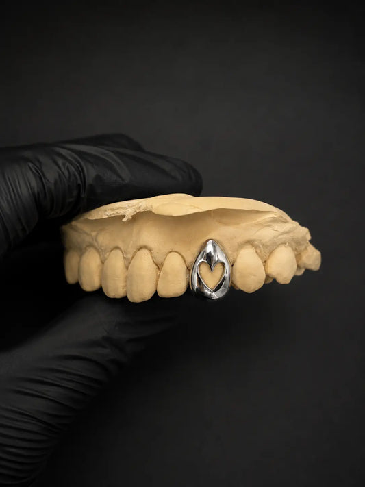 Custom hollow heart gold grillz tooth cap on dental mold with black background