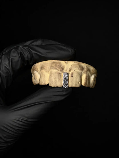 Handmade iced out diamond gap grillz with custom gemstone tooth cap displayed on black background with black gloves