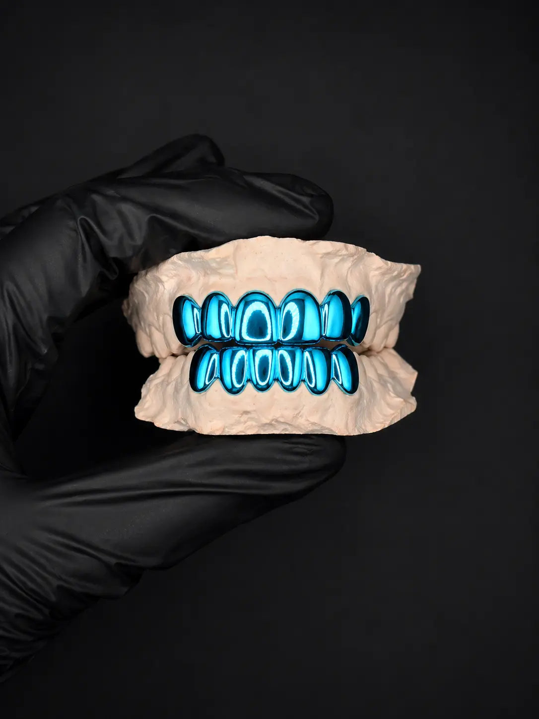 Glowing blue grill on a black background held by a black-gloved hand.