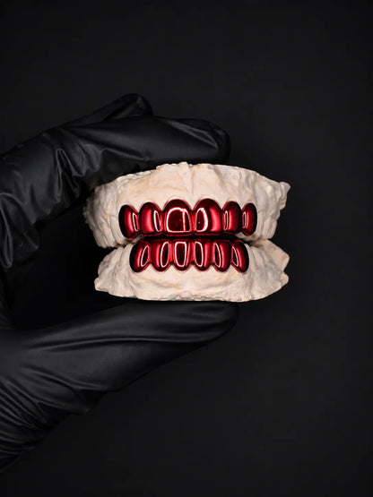 Glove holding a set of dentures with red metalwork on a black background