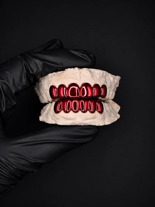 Glove holding a set of dentures with red metalwork on a black background