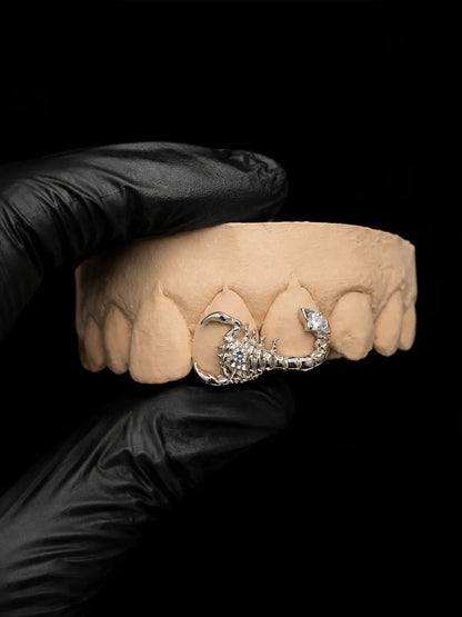 Vertical luxury product photo of custom silver scorpion grillz with white gemstone accents