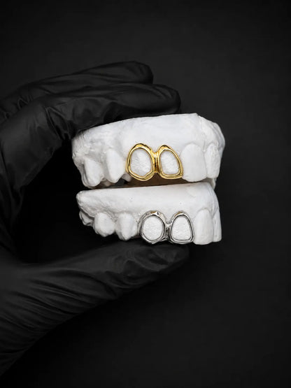 Single tooth custom open face grill on a white dental model held with a black glove