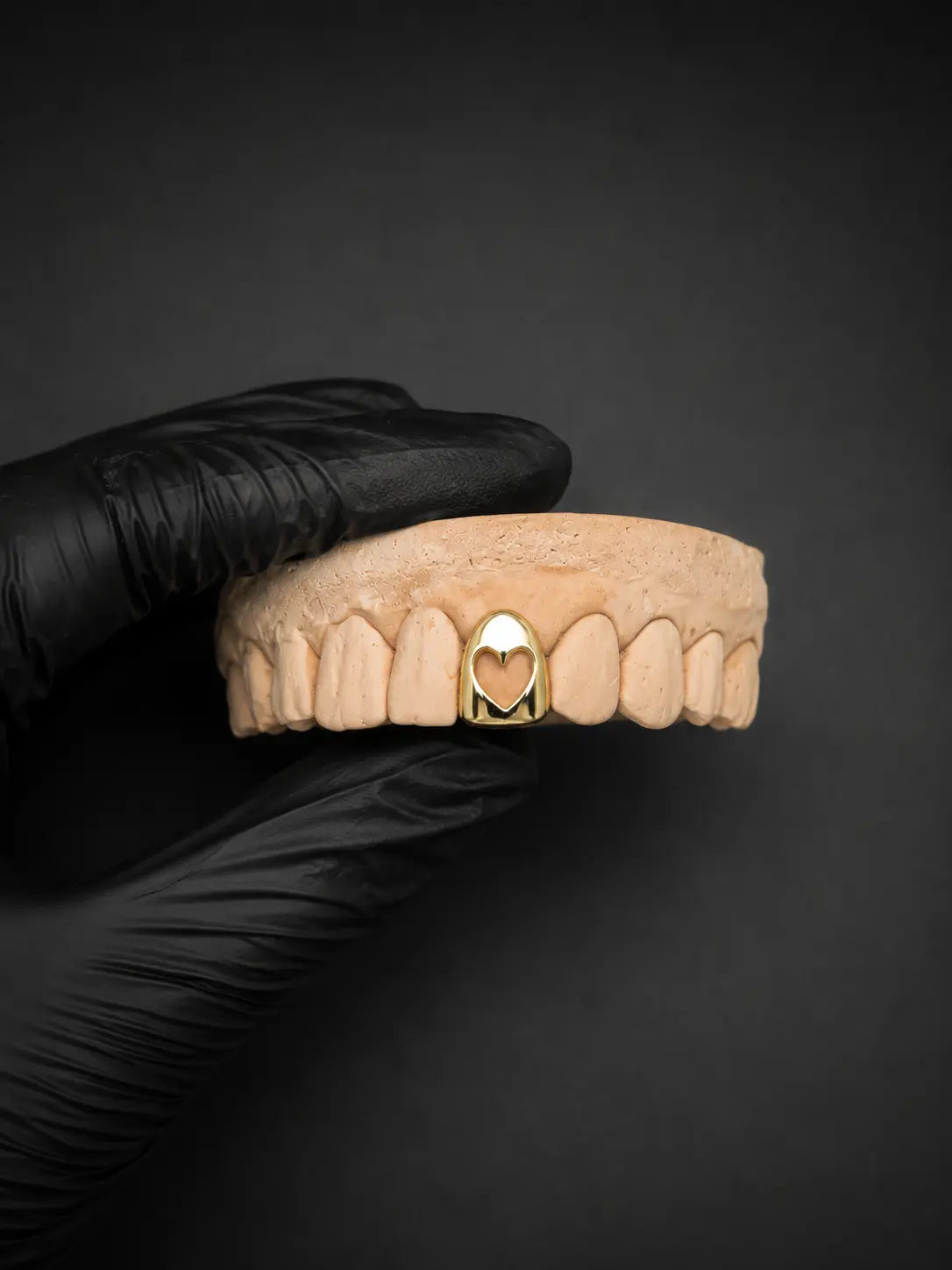 Luxury custom heart grillz displayed with black glove and dark background