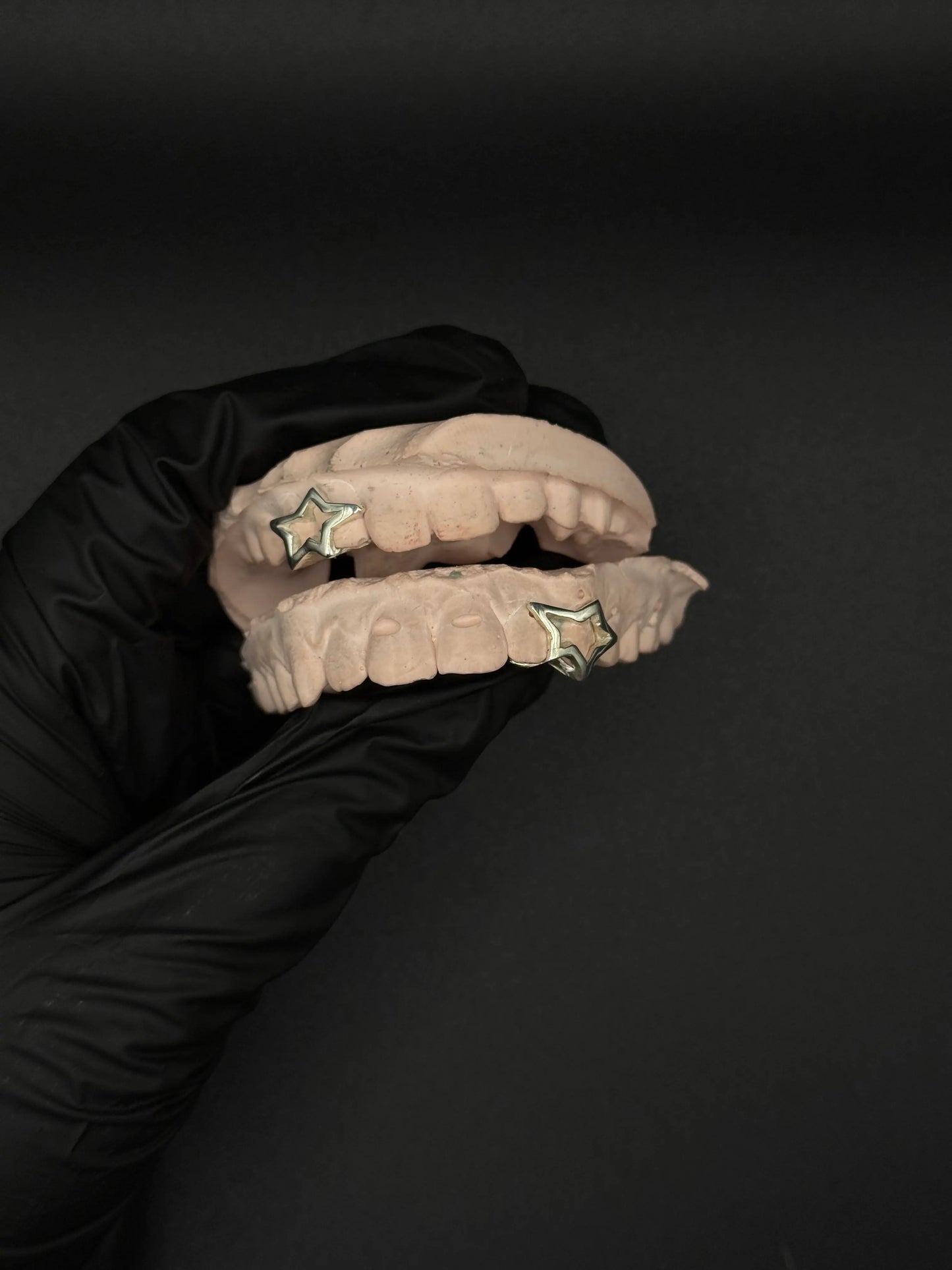 Close up of custom star shape grillz with polished silver and gold detailing